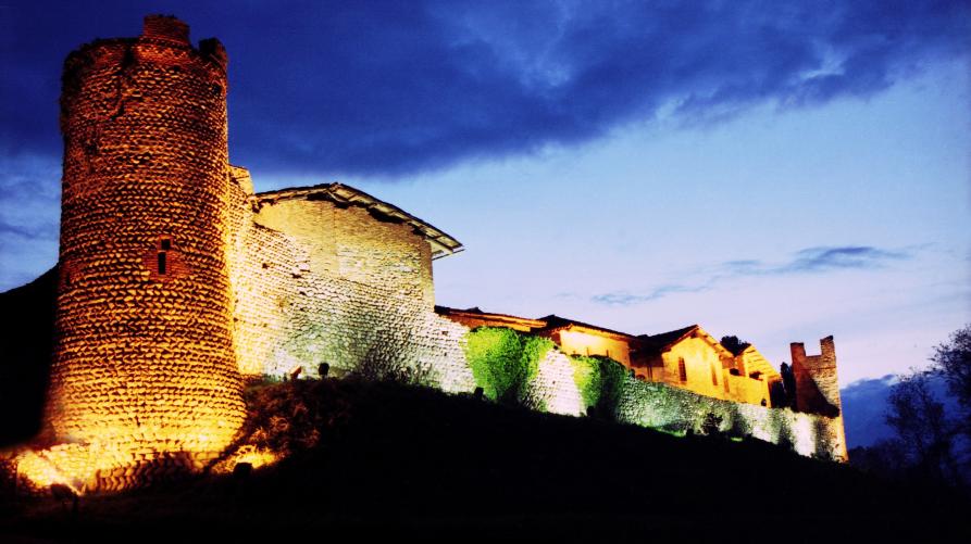 Candelo (BI). Il ricetto è illuminato da luci calde all'imbrunire. Il cielo blu cobalto e sfuma a sinistra verso l'azzurro intenso
