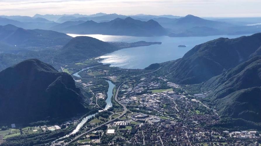 Gravellona Toce (VCO). Panoramica aerea del paese. Il fiume si allunga fino al lago. Sullo sfondo le montagne e il cielo solcato da nuvole 