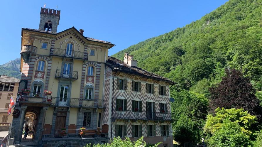 Rosazza (BI). L'edificio ottocentesco del Municipio presenta quattro piani. Le finestre sono decorate con motivi a righe color mattone e crema. Il cielo è terso  