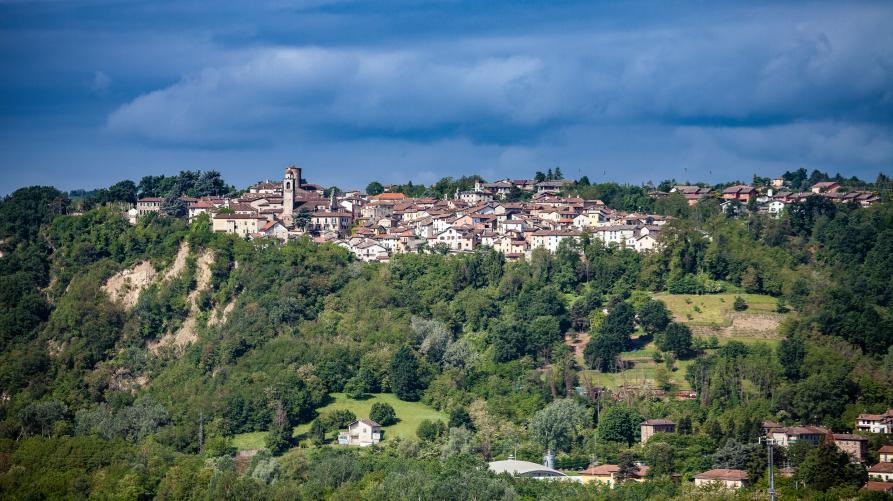 Rocca Grimalda (AL). Il paese arroccato sulle colline verdi è visto in lontananza. Il cielo è blu  