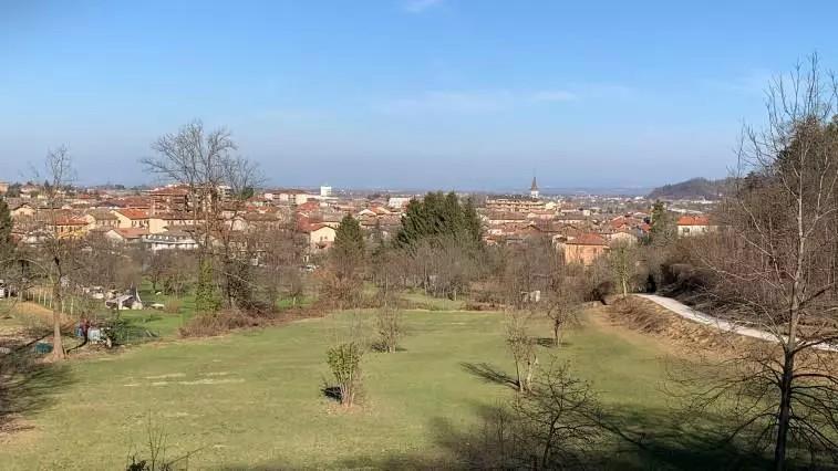 Borgo San Dandalmazzo. Il cielo azzurro tocca le case in lontananza. In primo piano un grande prato verde e alberi ancora spogli. Immagine tratta dal sito del Comune (2025) 
