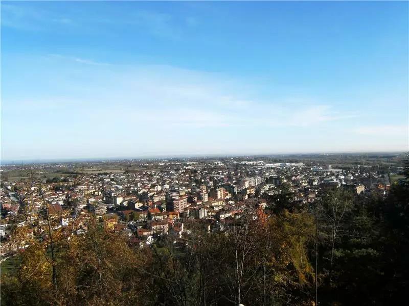 Borgo San Dalmazzo (CN). Nella metà inferiore la vegetazione e i tetti delle case in lontananza sfiorano il cielo azzurro che occupa la metà superiore della fotografia. Immagine tratta dal sito del Comune (2025) 