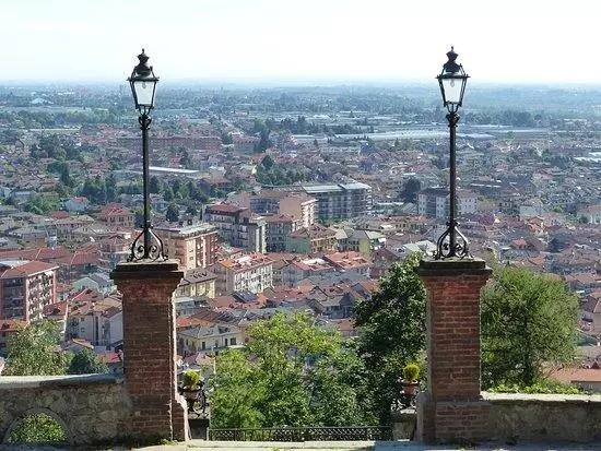 Borgo San Dalmazzo (CN). Il Comune visto in lontananza dal Santuario del Monserrano fra due colonne in mattoni sormontate da due lampioni. Immagine tratta dal sito del Comune (2025) 