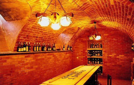 San Damiano d'Asti (AT). La bottega del vino con volte in mattoni a vista. Due lampadari illuminano il locale che custodisce le bottiglie di vino lungo le pareti  