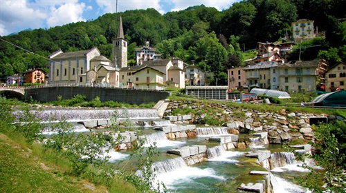 Fobello (VC). Il paese sullo sfondo immerso nel verde. Il fiume scorre ai piedi del paese con balzi e cascatelle 