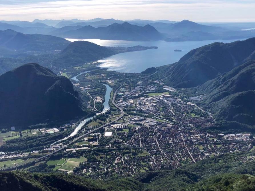 Gravellona Toce (VCO). Panoramica aerea della città minuscola che si allunga verso il lago Maggiore. Il colore dominante della fotografia è l'azzurro  