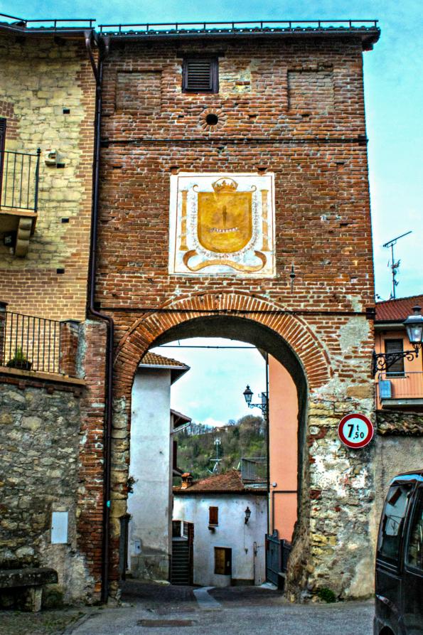 Castelletto d'Orba (AL). Arco in mattoni rossi sormontato da stemma ocra in campo bianco (2014) 