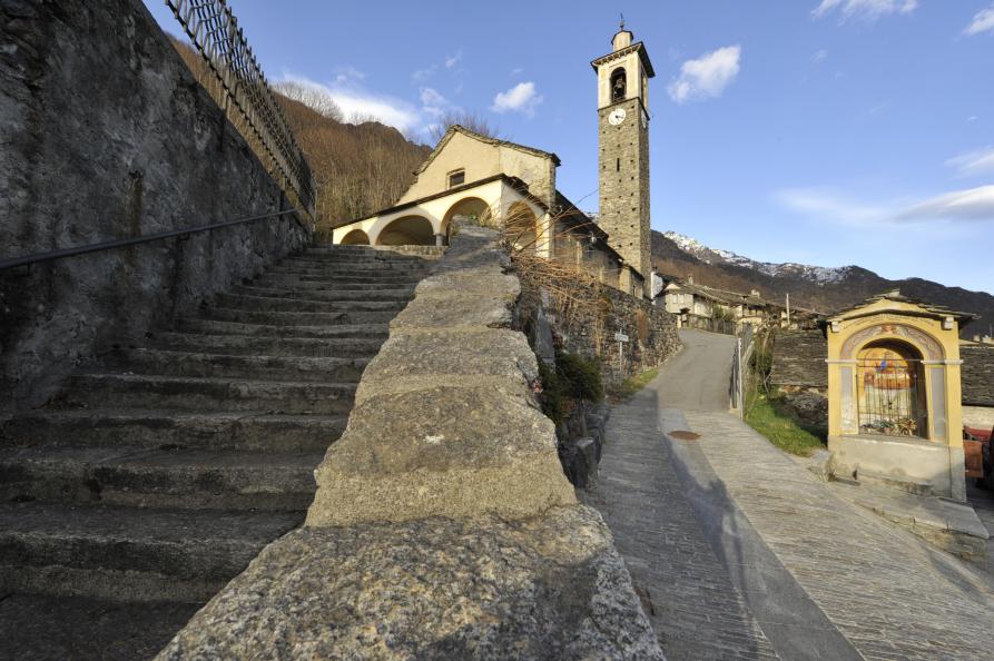 Premosello-Chiovenda (VCO). Oratorio di San Gottardo inquadrato dal basso. Una scalinata in pietroni conduce alla chiesa e al suo campanile 