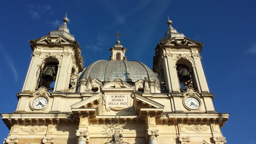 Boves (CN). Santuario della Regina della Pace (frazione Fontanelle). Inquadratura della facciata superiore. A lato della cupola rivestita in lamine di metallo svettano i due campanili con orologi. Fotografia di Giorgio Vannucchi 
