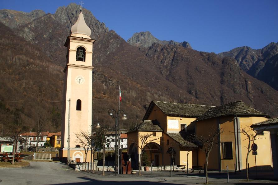 Premosello-Chiovenda (VCO). Chiesa di San Martino a Cuzzago. In alto il cielo blu terso e le montagne. A sinistra il campanile staccato dalla chiesa inquadrata lateralmente 