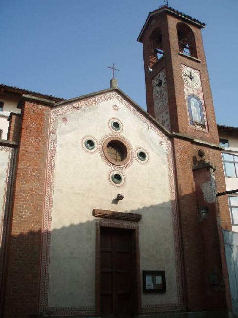 Agliè (TO). La  Chiesa di San Rocco è in stile neo-romantico La facciata semplice tinteggiata di bianco con il rosone centrale in alto e il campanile in mattoni rossi con l'orologio e la statua del Santo. Immagine tratta dal sito del Comune (2025). 