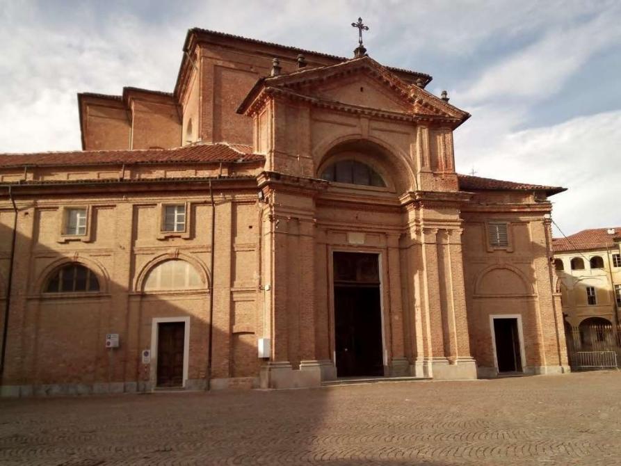 Agliè (TO). Dalla piazza lastricata si accede al Parrocchiale di San Massimo in puro stile Barocco piemontese. Dominano i mattoni rossi a vista.. Immagine tratta dal sito del Comune (2025). 