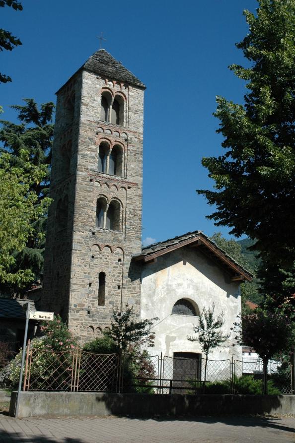 Condove (TO). In mezzo a due grandi alberi si erige, a sinistra, l'alto campanile romanico in pietre grigie affiancato dalla piccola Chiesa di San Rocco. Fotografia di Erica Gambelli (2009) 