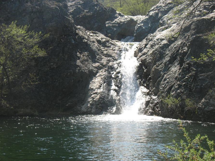 Pareto (AL). In primo piano il Lago Scuro. La cascata a due salti spacca a metà le nude rocce grigie. Immagine tratta dal sito del Comune (2025) 