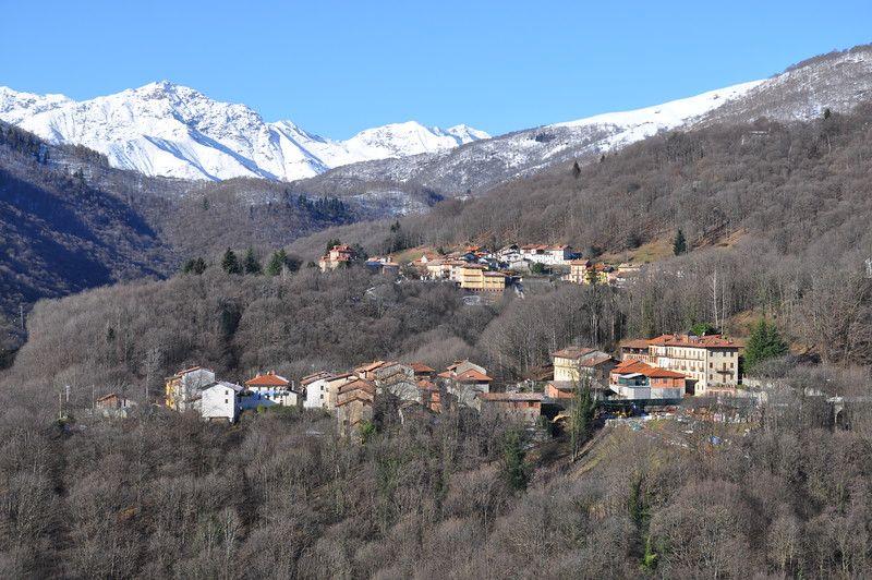 Camandona (BI). Panoramica delle frazioni alte immerse fra i boschi spogliati dall'inverno. Sullo sfondo le montagne di Oropa imbiancate dalla neve. Immagine di Ilario Guelpa Piazza 