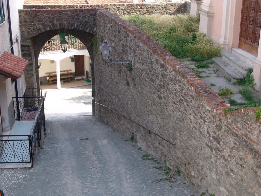 Pareto (AL). Porta dei Borreani: arco in pietre e mattoni con due lampioni e a destra muraglia in pietre e mattoni. Immagine tratta dal sito del Comune 