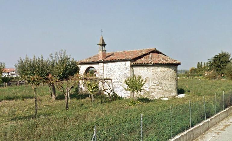 Farigliano (CN). Dal prato verdeggiante emerge il retro della cappella romanica di San Nicolao in pietre e mattoni a vista. 