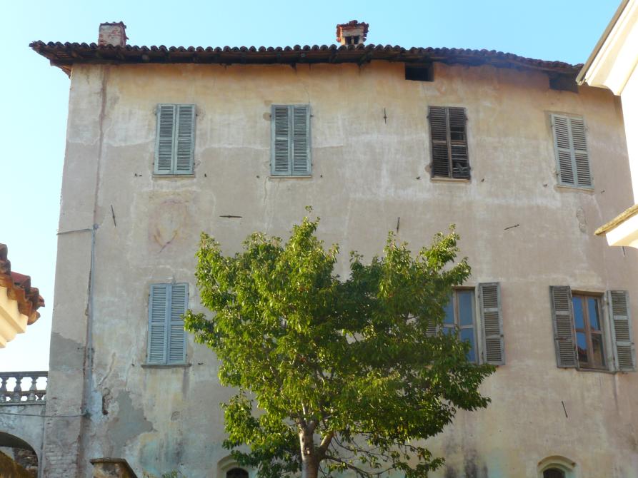 Lozzolo (VC). Porzione laterale del Castello. L'edificio presenta una serie di finestre con scuri di legno tinti di grigio. La chioma di un albero copre la zona centrale della fotografia.  
