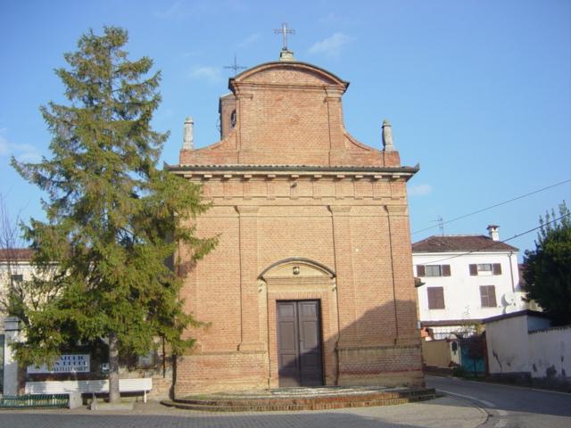 Gamalero (AL). La Chiesa di San Rocco, in barocco piemontese, con mattoni a vista su tutta la facciata e portale lineare in legno. A sinistra un alto albero verde 