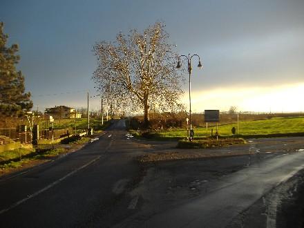 Gamalero (AL). Paesaggio dopo la pioggia. Il cielo grigio ha uno squarcio di luce in basso a destra che illumina prati e alberi  