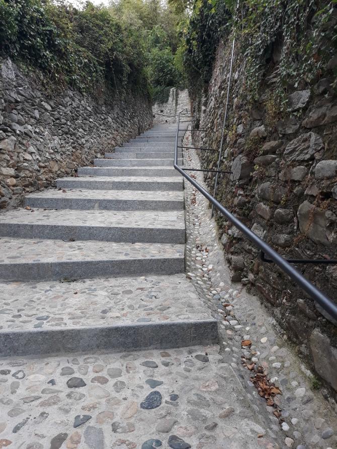 Bricherasio (TO). Scorcio della scalinata storica lungo la collina del castello affiancata da alti muretti in pietra ricoperti di vegetazione  