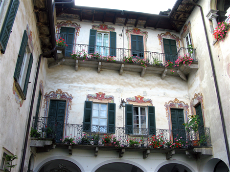 Nonio (VCO). Facciata di Villa Tarsis. Si intravedono le arcate del piano terra e al secondo e terzo piano due balconate in ferro battuto con una serie di finestrature decorate con motivi floreali con persiane di legno verde bottiglia. Immagine tratta dal sito del Comune (2025)  