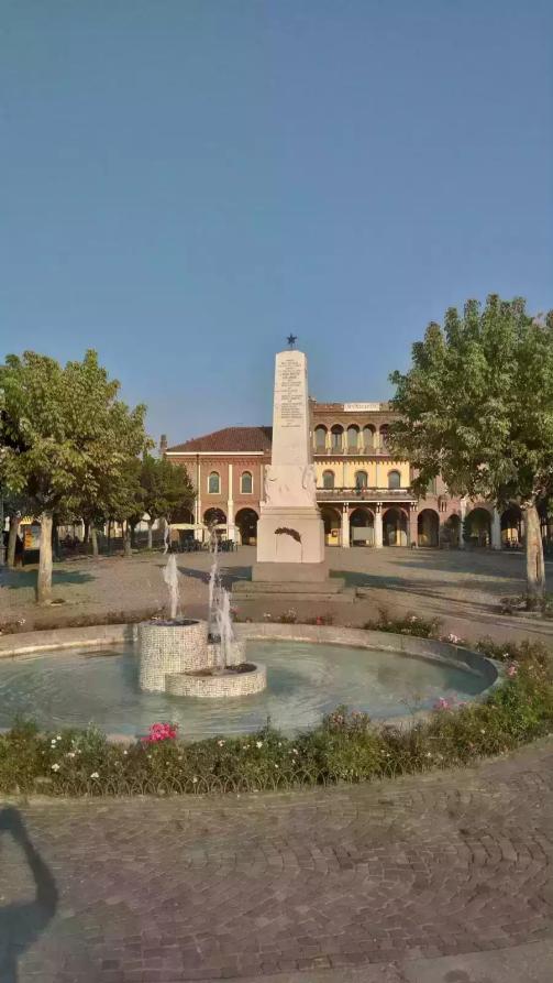 Sezzadio (AL). Vista di Piazza della Libertà con fontana e obelisco centrale. Al fondo il palazzo municipale affiancato dagli alberi. Immagine tratta dal sito del Comune (2025) 