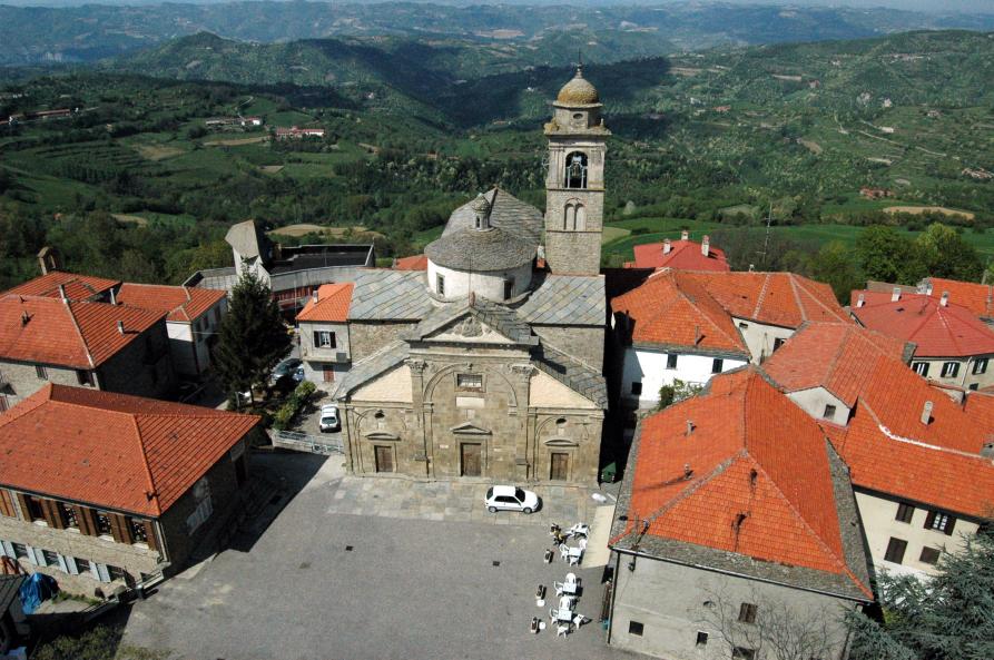 Roccaverano (AT). Vista dall'alto della Chiesa Parrocchiale bramantesca del 1500 affacciata sulla storica piazza. Intorno i tetti rossi delle case e sullo sfondo le colline verdeggianti 