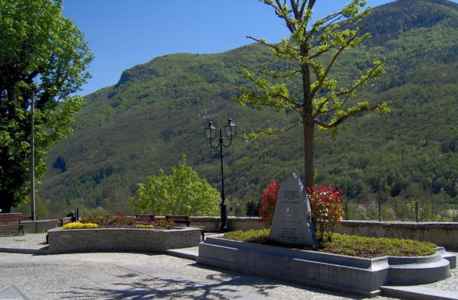 Villa Pellice (TO). Il monumento a Willy Jarvis e sullo sfondo le montagne verdeggianti. Il cielo è blu intenso 