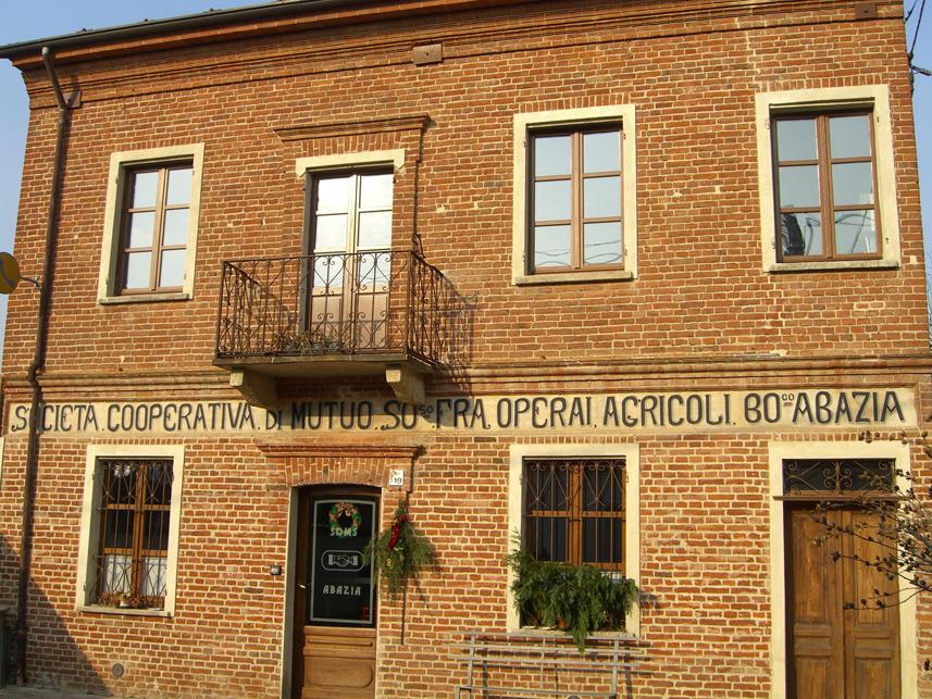 Masio (AL). L'edificio sobrio e lineare della Società Operaia di Mutuo Soccorso è a due piani e rivestito in mattoni rossi 