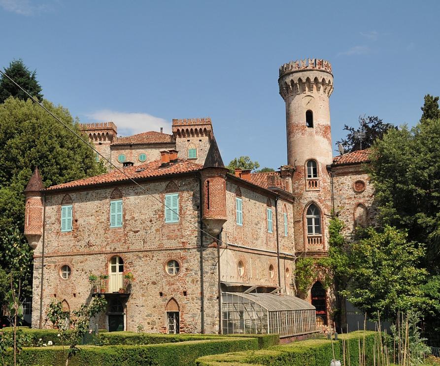 Vigliano Biellese (BI). Il Castello Montecavallo in stile neogotico si erge fra la vegetazione rigogliosa e le siepi curate del suo giardino. Il cielo è azzurro 