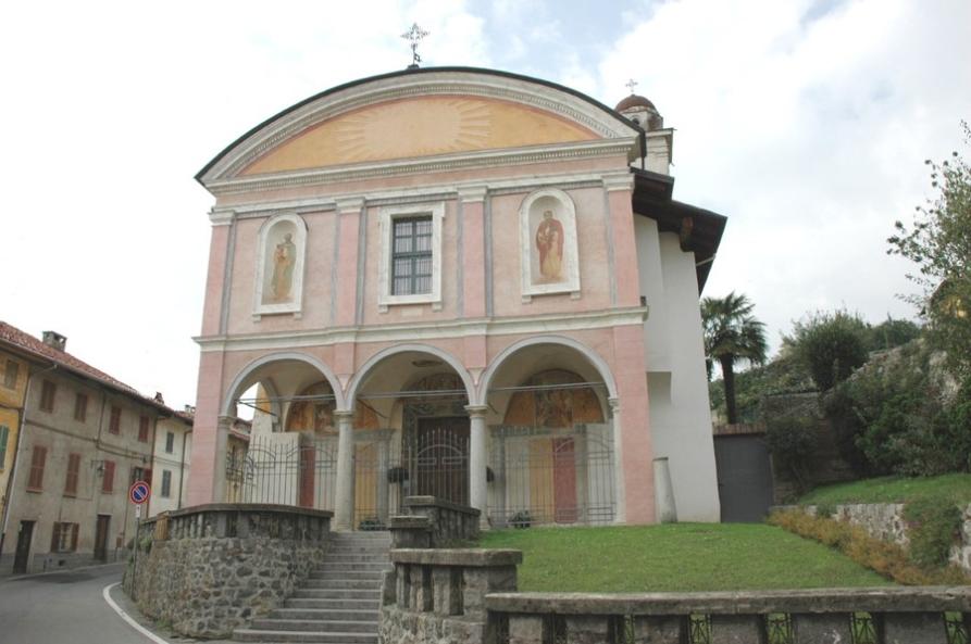 Vigliano Biellese (BI). Una gradinata conduce al porticato corredato da tre arcate. Al centro l'entrata principale della Chiesa di S. Lucia. La facciata dipinta di rosa è decorata con affreschi 