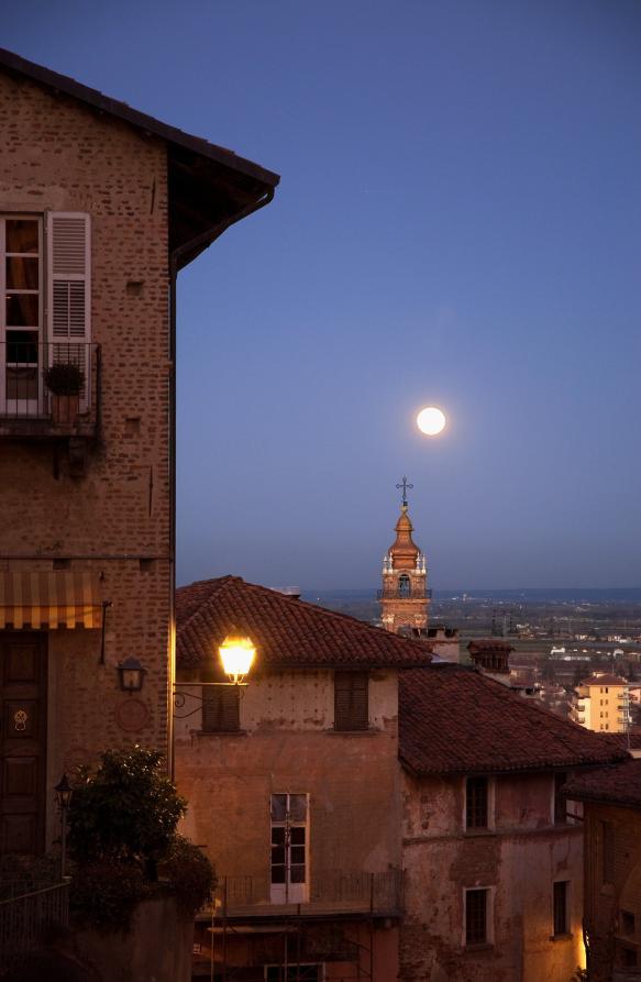 Saluzzo (CN). Scorcio panoramico notturno delle case del paese con luna piena. 