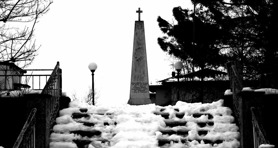 Caresana (VC). Scorcio in bianco e nero di una scalinata innevata che conduce a un obelisco commemorativo. Fotografia di Andrea Cherchi (2009) 