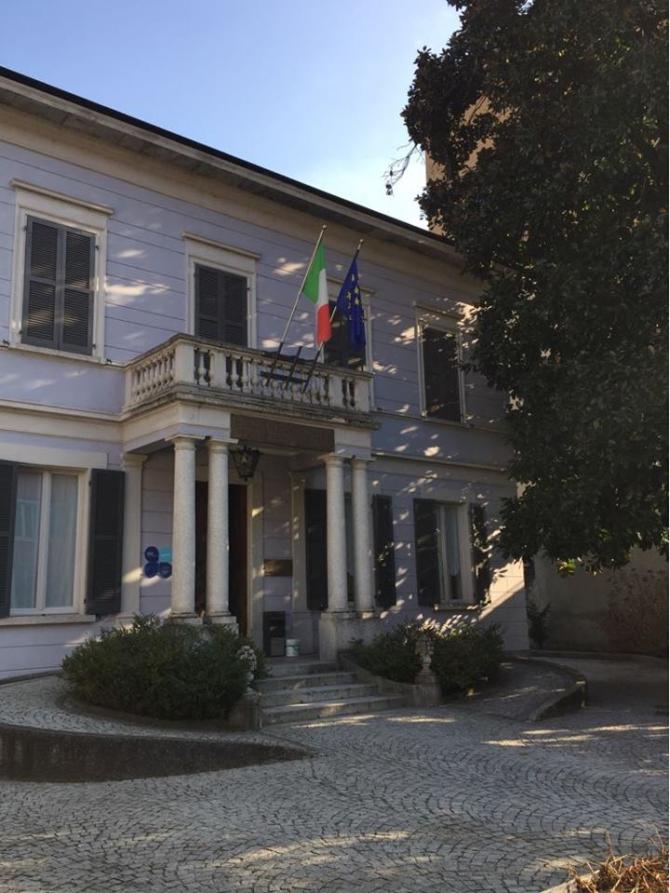 Gravellona Toce (VCO). La biblioteca. Edificio a due piani con piccolo balcone sopra alla porta di entrata e doppia serie di colonne al piano terreno da cui si dirama una serie di gradini  che conducono allo spiazzo davanti all'edificio. 