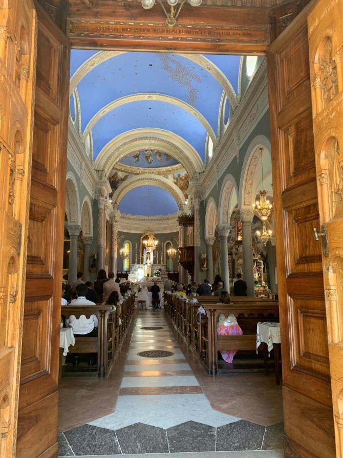 Rosazza (BI). Il portale spalancato di legno chiaro della Chiesa dei Santi Pietro e Giorgio permette di ammirare il soffitto azzurro e stellato della chiesa 