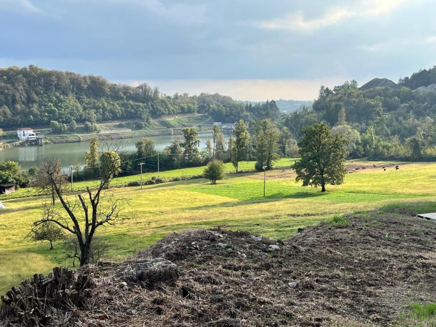 Vidracco (TO). I prati scoscesi e verdeggianti conducono alla riva del lago. Sull'altra sponda la collina. Il cielo è nuvoloso 