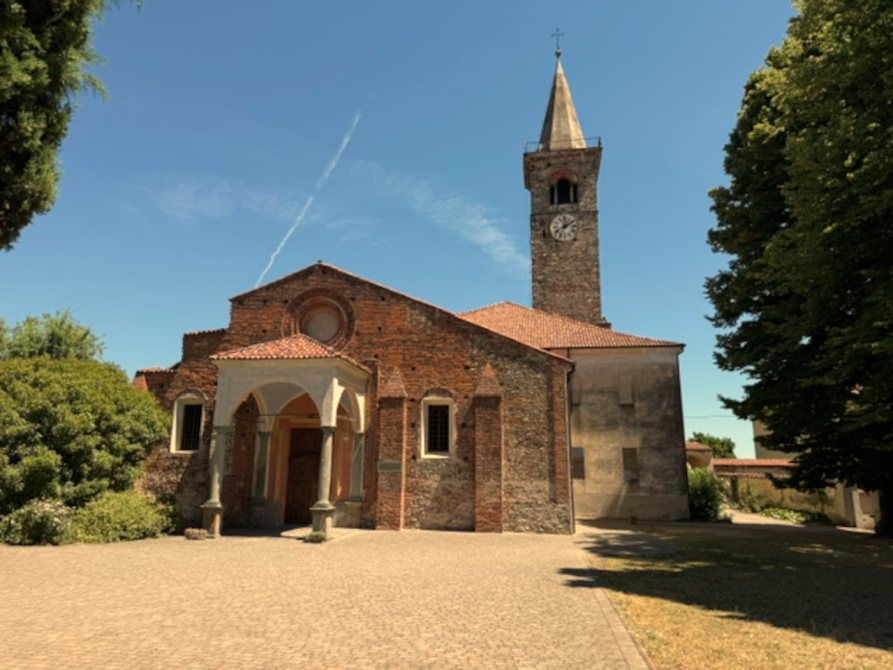 Salussola (BI). Vista della Chiesa di Santa Maria Assunta di Salussola, edificio storico in mattoni con facciata romanico gotica, campanile e porticato, inserito nel contesto del borgo storico. Il cielo è azzurro. Fotografia di Francesco Spina 