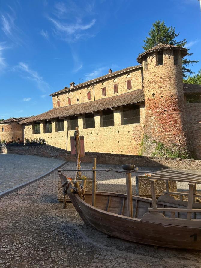 Castelletto Molina (AT). La barca color legno è il punto di partenza del percorso "Come una barca nelle vigne". Alle spalle il Castello dei Conti Veggi. Il cielo è blu  
