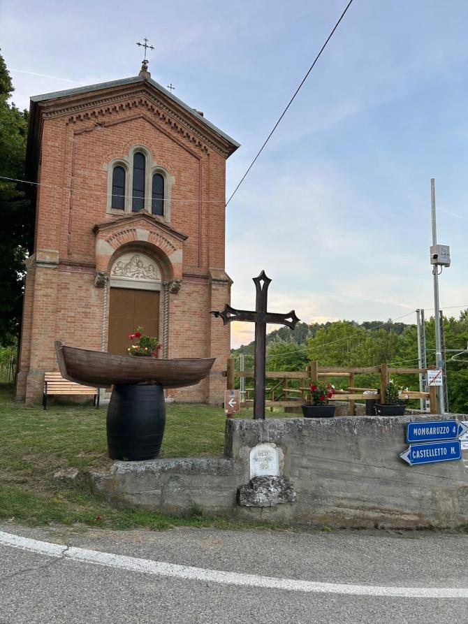 Castelletto Molina (AT). Facciata in mattoni rossi del Santuario della Madonna della neve. In primo piano una barchetta di legno parte del percorso "Come una barca nelle vigne" 