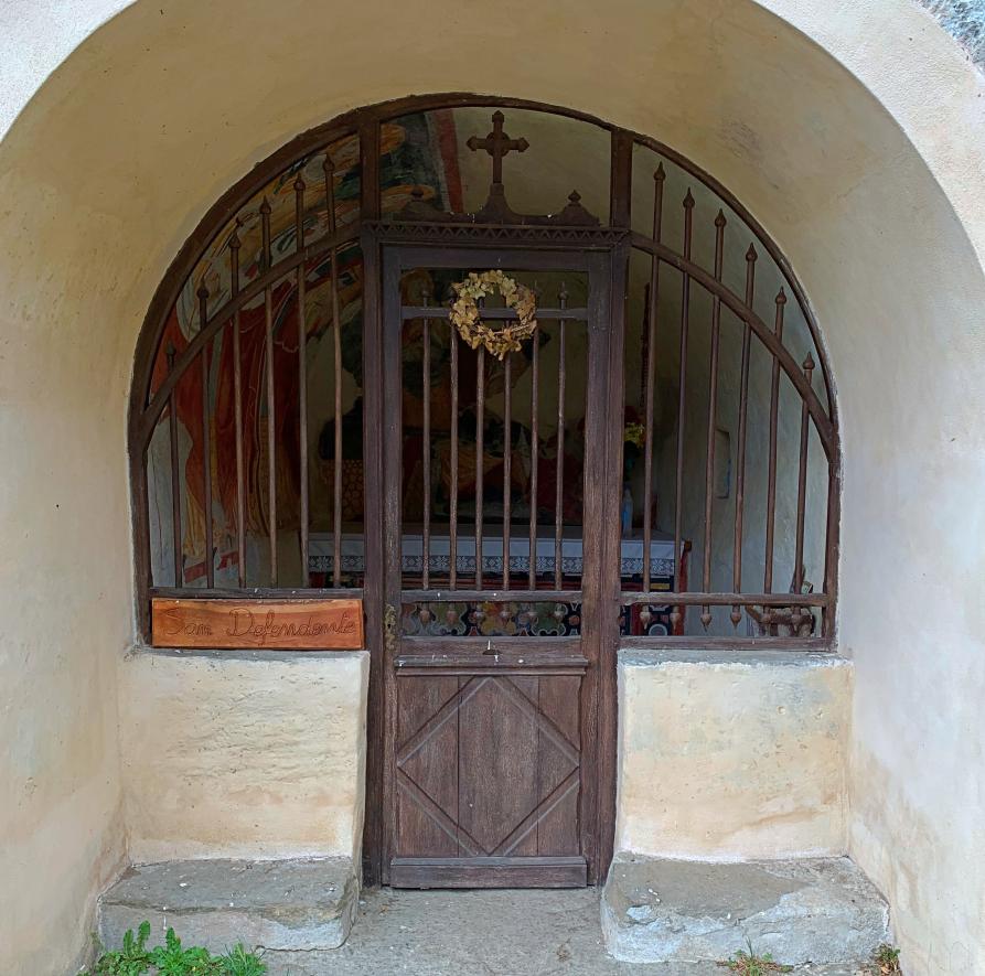 Mollia (VC). La piccola Cappella San Defendente con portoncino e grata in legno che lascia intravedere degli affreschi dipinti sulla volta e parte frontale dell'altare 