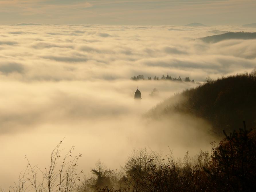 Mombarcaro (CN). Dal mare di nebbia emerge a destra la punta finale del campanile della chiesa della Madonna delle Grazie 