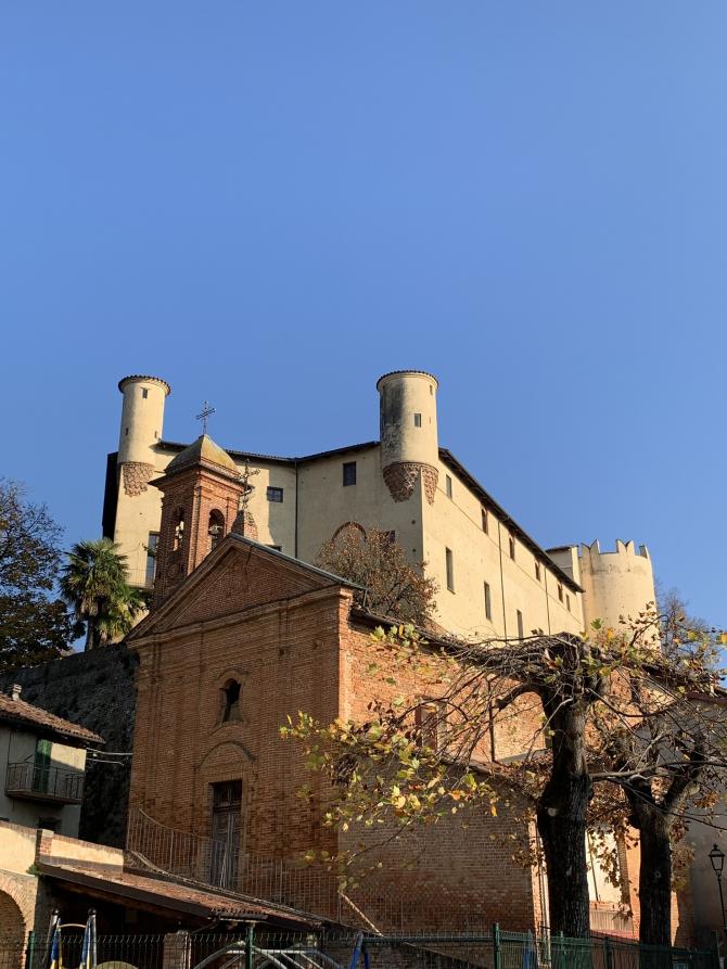 Cortanze (AT). La Chiesa romanica della S.S. Annunziata in mattoni rossi a vista è sovrastata dal castello. Il cielo è limpido 