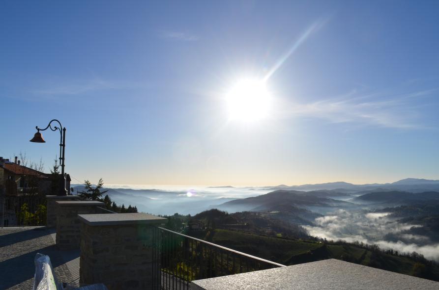 Mombarcaro (CN). Panorama delle valli con nebbia. In alto il cielo è terso e splende il sole 